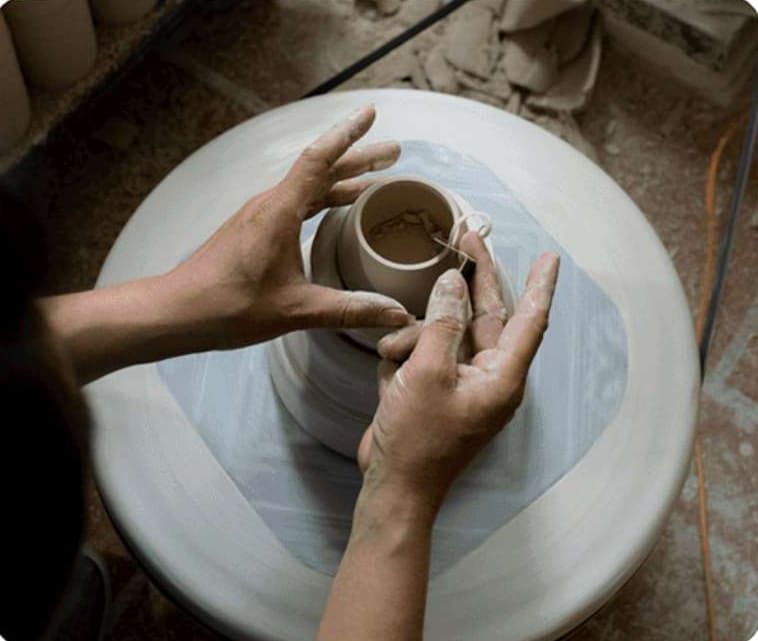 An artisan shaping a cup on the potter's wheel