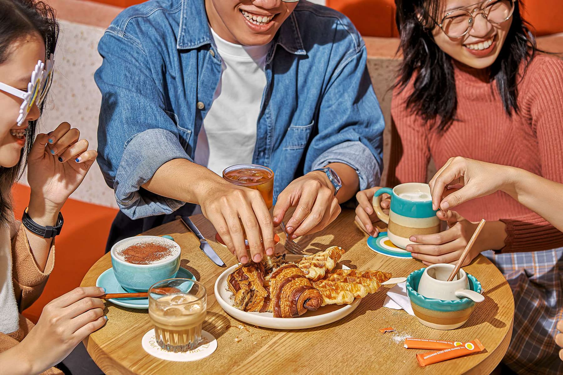 Friends sharing egg coffee, lattes and croissants at an Eggyolk table